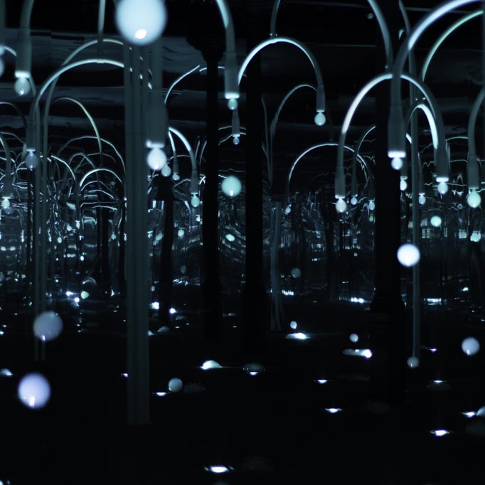 A dark image with an immersive installation creatively illuminating the scene of crafted trees blowing out lighten bubble.