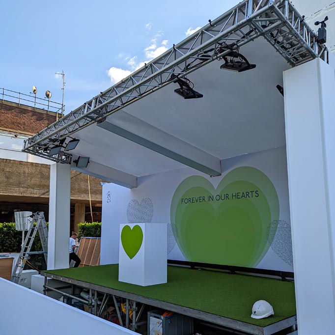 White and green stage with a green heart, with rigging and lighting fixed to the stage
