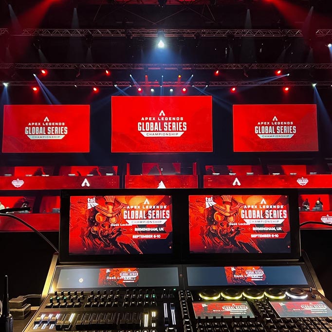 Lighting desk at the front and screens ahead, all set in red, with lighting illuminating the scene