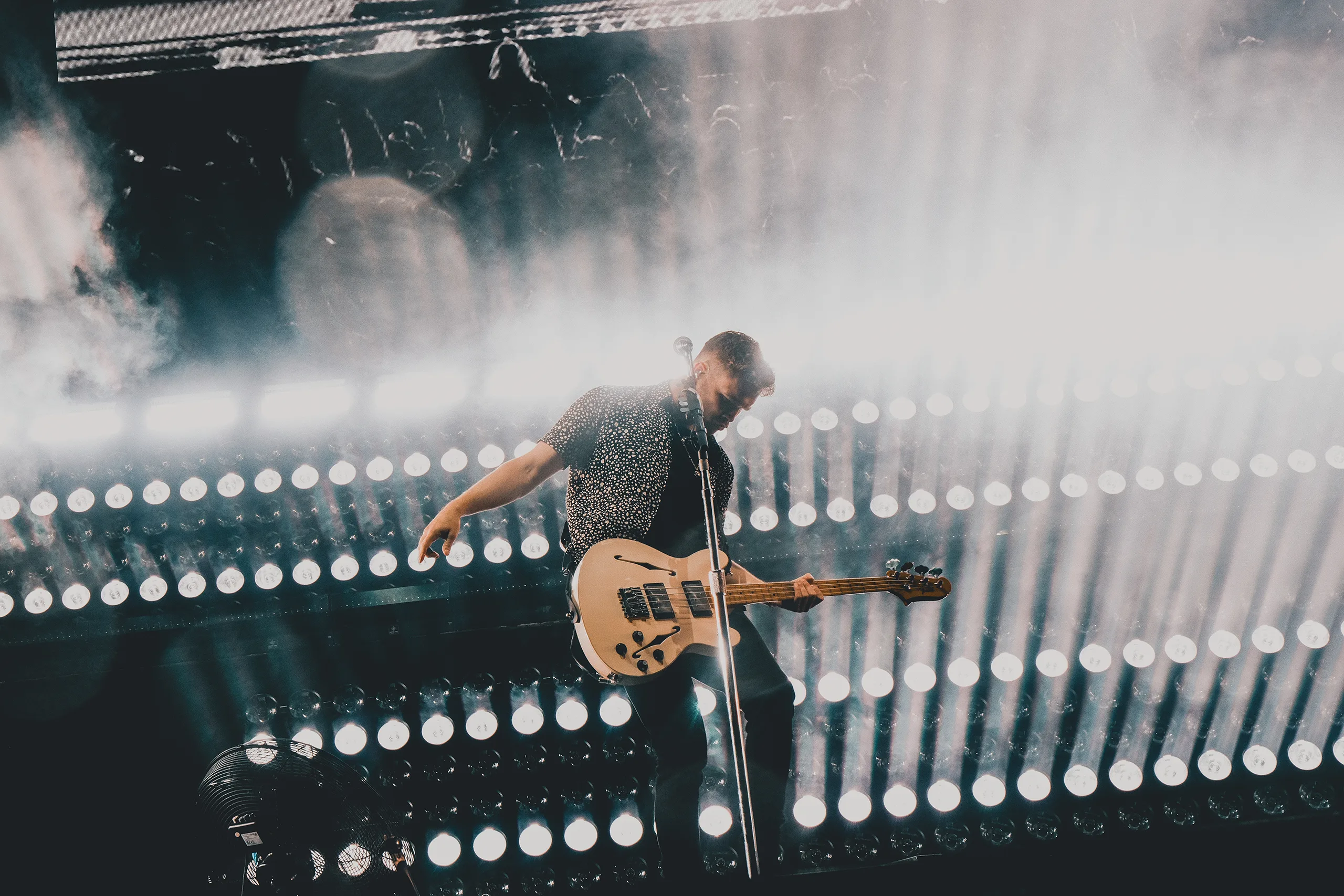 royal blood band member playing the guitar, with a background of lighting